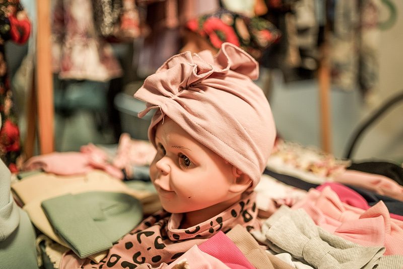Różowy turbanik niemowlęcy na ekspozycji wśród ręcznie szytych czapeczek